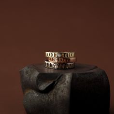 two gold rings sitting on top of a wooden block