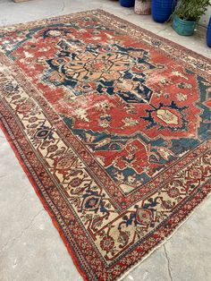 an old rug is laying on the ground in front of some potted planters