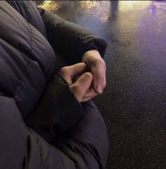 a person sitting on a bench with their hands folded out and lights in the background