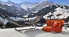 a hammock and sleeping bag in the snow with mountains in the back ground