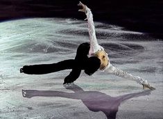 a man and woman skating on ice in front of the moon with their arms stretched out