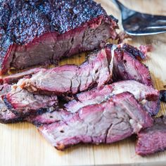 the meat is sliced up and ready to be eaten on the cutting board with a fork