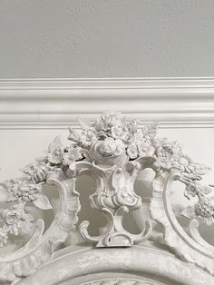 an ornate white fireplace surround with flowers on it