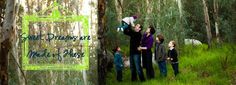 a group of people standing next to each other in a forest with trees and grass