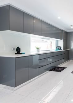 a large kitchen with gray cabinets and white counter tops, along with black rugs on the floor