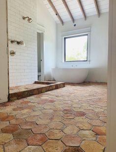 an empty bathroom with a large window and stone flooring in the middle of it