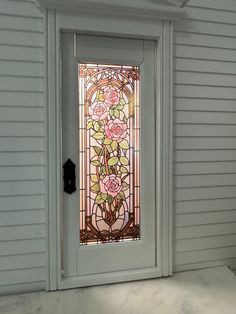 a stained glass door in front of a white house with flowers on the window sill