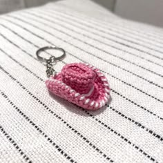 a pink crocheted hat keychain sitting on top of a bed