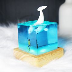 an ice cube with two dolphins in the water on top of it and a wooden base