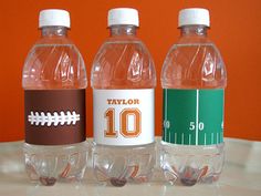 three bottled water bottles sitting on top of a white table next to an orange wall