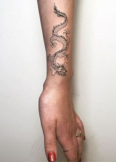 a woman's arm with a dragon tattoo on the left side of her arm