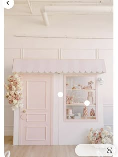 a pink store front with flowers in the window and an open door on the side