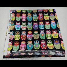 two pieces of fabric with colorful dolls on them, one is black and the other is multicolored