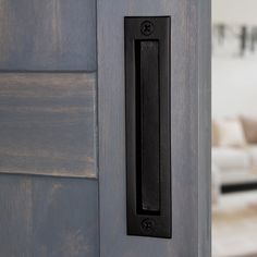 a door handle on a wooden door in front of a living room with a couch