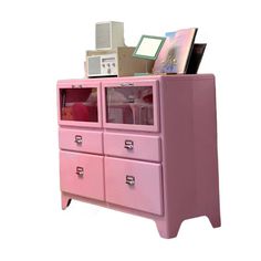 a pink dresser with drawers and pictures on it's top shelf in front of a white background