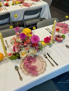 the table is set with plates, forks, and flowers on it for a formal function