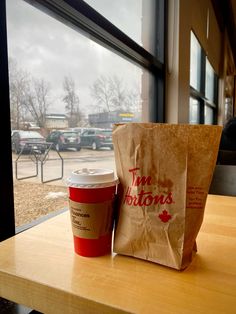 a cup of coffee sitting on top of a table next to a bag