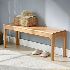 a wooden bench sitting in front of a wall with a basket on top of it