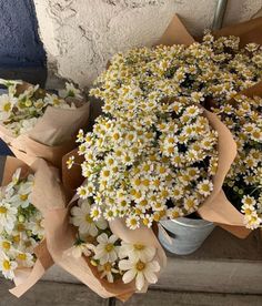 several bouquets of white and yellow daisies on display in front of a wall