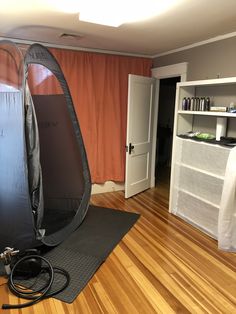 a photo studio setup up in a living room with hard wood flooring and orange drapes