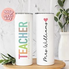 two personalized tumbles with the words teacher and heart on them sitting on a wooden tray