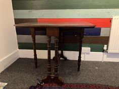 a small wooden table sitting on top of a carpeted floor next to a radiator