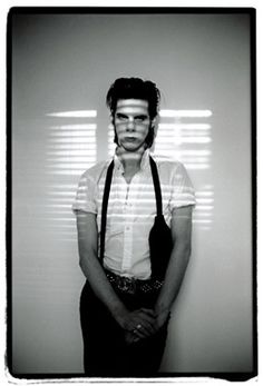 a man standing in front of a wall wearing suspenders