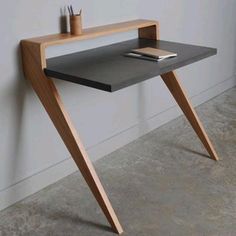 a wooden table with a book on it next to a white wall and a window