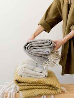 a woman is stacking blankets on top of a table