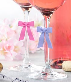 two wine glasses with pink and purple bows on them