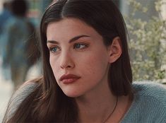 a close up of a person wearing a sweater and looking at the camera with a serious look on her face