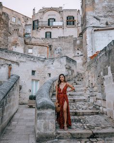 a woman in a red dress is standing on some stairs and looking at the camera