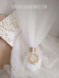 a white vase sitting on top of a bed next to a card and some paper