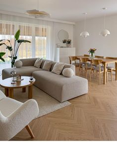 a living room filled with furniture next to a wooden table and chairs on top of a hard wood floor