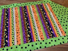 a green table mat with black and orange strips on it, sitting on top of a wooden floor