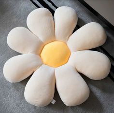 a white flower shaped pillow sitting on top of a carpet