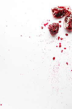 pomegranates and seeds on a white surface