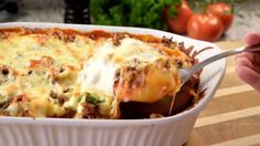 a casserole dish filled with meat and cheese being held by a person's hand