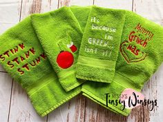 three green towels with embroidered sayings on them