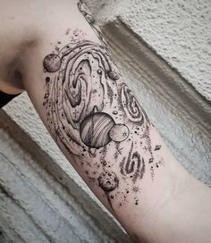 an arm tattoo with planets and stars on the outer half of it, in black ink