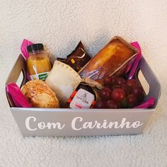 a box filled with different types of food on top of a white blanket next to a bottle of juice