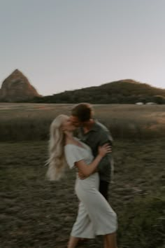 a man and woman are kissing in an open field