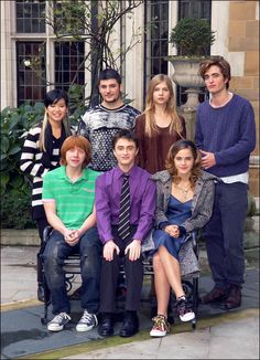 a group of people sitting on top of a bench in front of a building next to each other