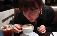 a woman sitting at a table with a cup and saucer in front of her