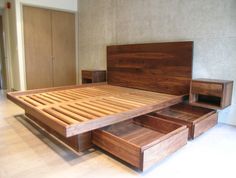 a wooden bed with two drawers underneath it