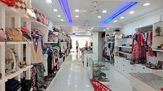 a woman is walking down the aisle in a store with lots of clothes on shelves