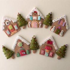 small felt houses are arranged in a circle on a white surface with christmas trees and snowmen