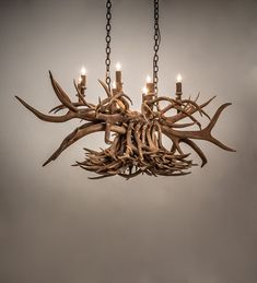 a chandelier made out of antlers hanging from chains with candles in them