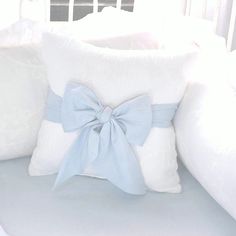 a white couch with two pillows and a blue bow on the pillow cover that is attached to it