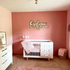 a baby's room with pink walls and white furniture